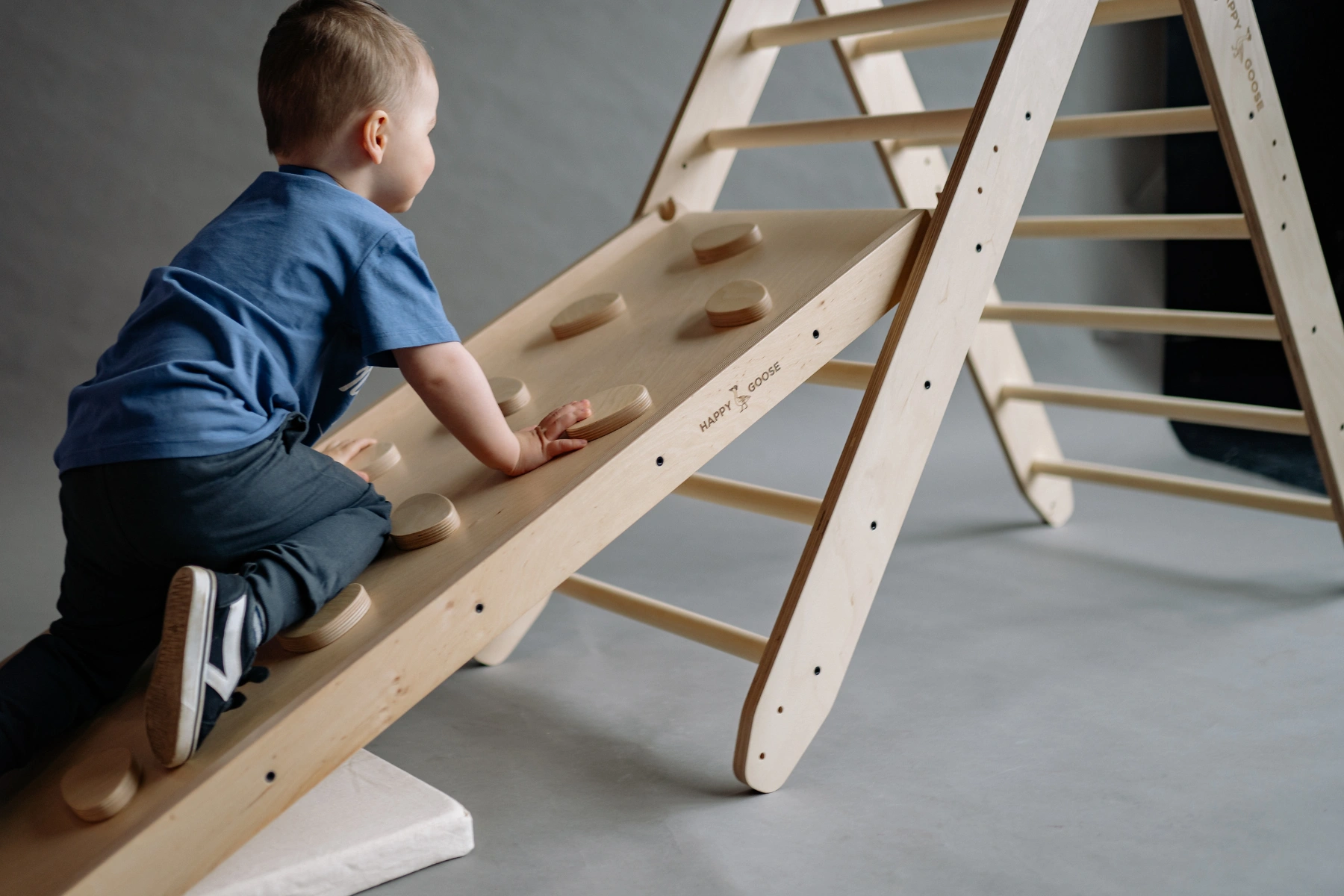 Little Boy Climbing Up a Wooden Climbing Wall on an Indoor Playground